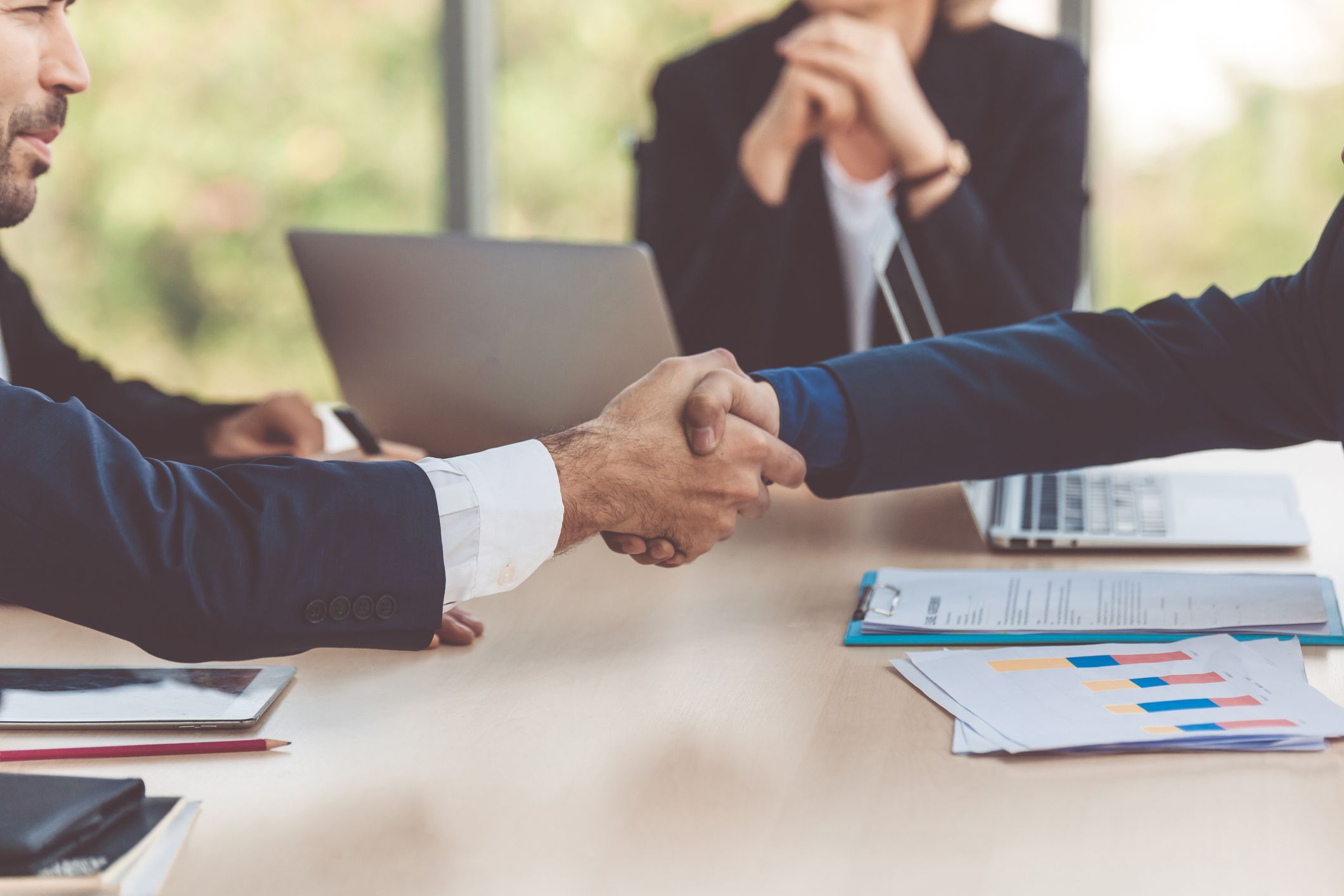 Twee zakenpartners schudden elkaar de hand tijdens een overleg.